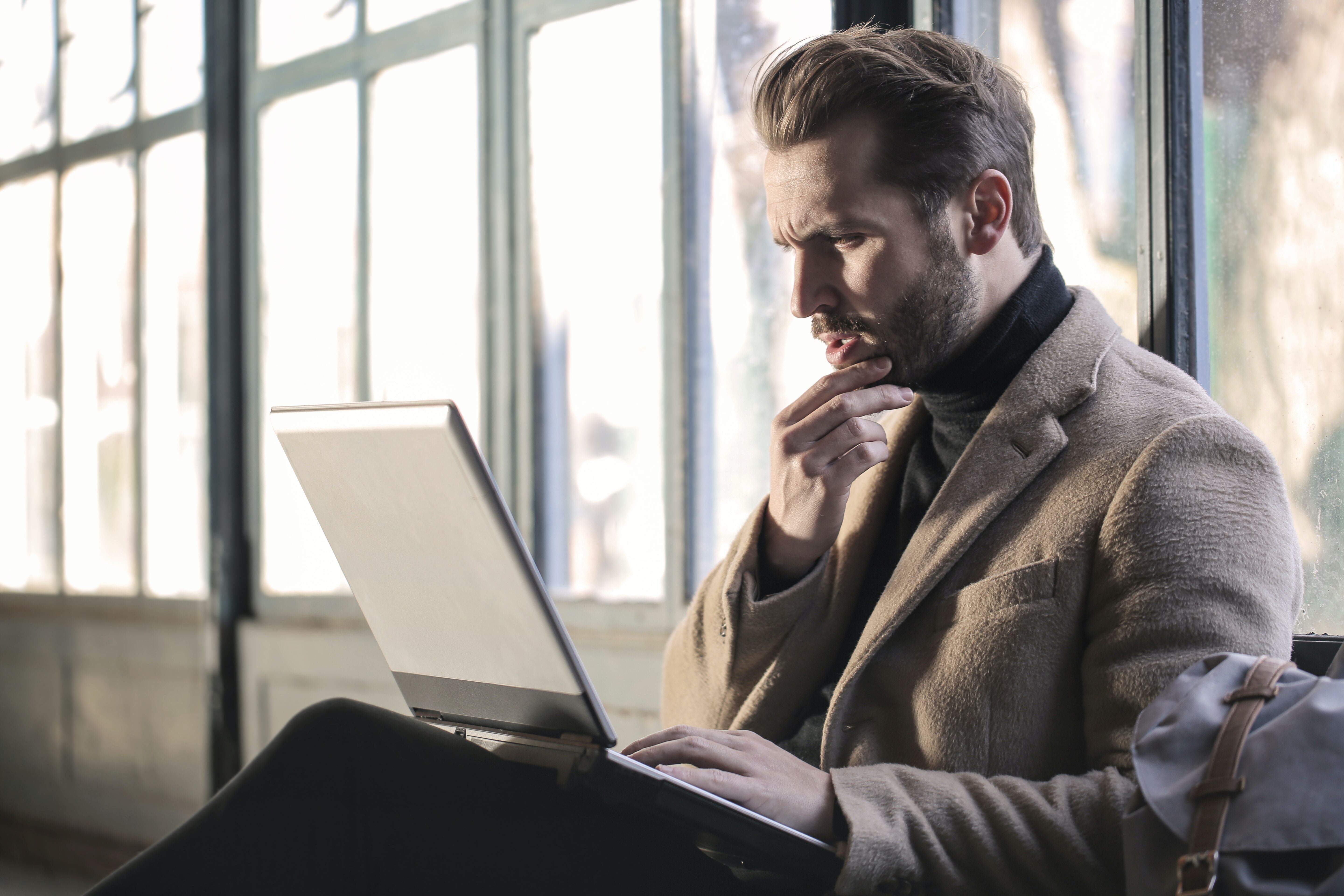 A man looking at a computer and thinking.