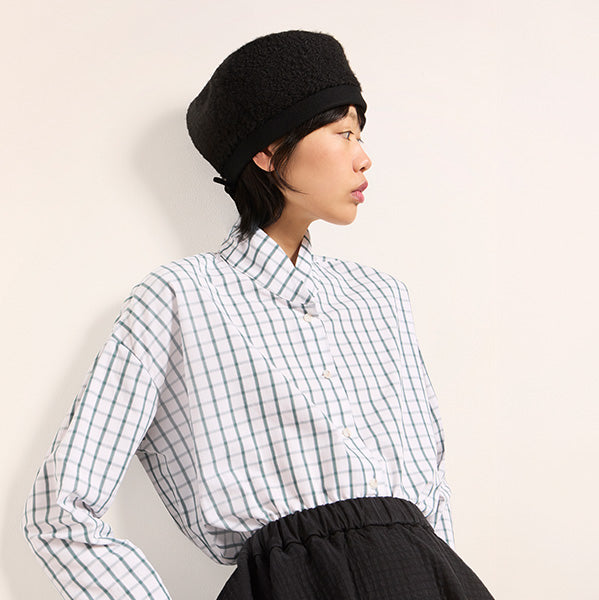 Plümo editorial photograph of a model in a checked shirt and black hat